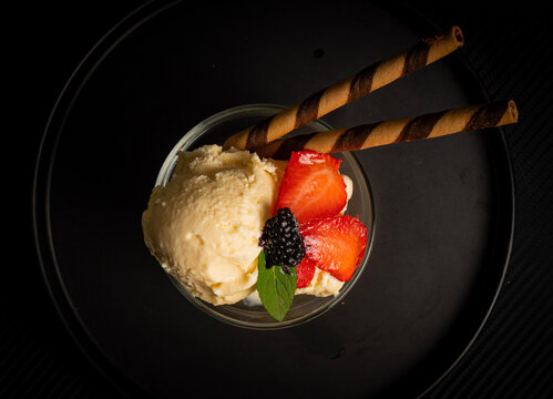 Helado de vainilla con fresas, ar&aacute;ndanos y galleta en tubo servida en copa