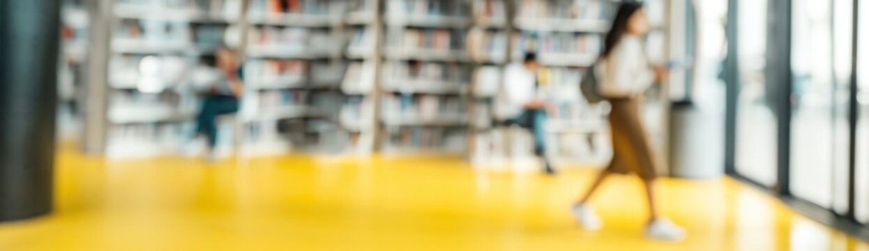 Person walking past book stacks near glass wall in library