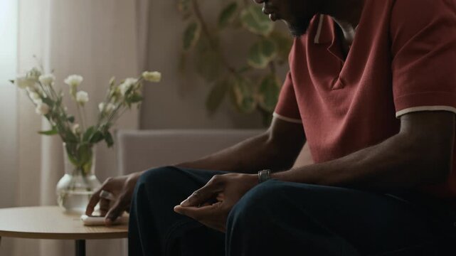Stab close up shot of young adult African American man with diabetes performing fingerstick blood test then measuring sugar level using glucometer during routine chronic condition management at home