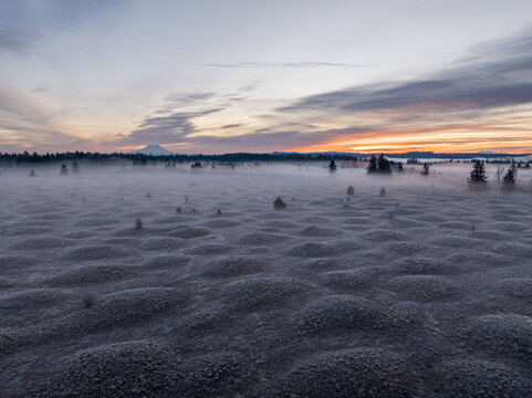 Aerial view of Mima Mounds Natural Area Preserve featuring frost-covered mounds under a misty sunrise sky Olympia, Washington, United States.