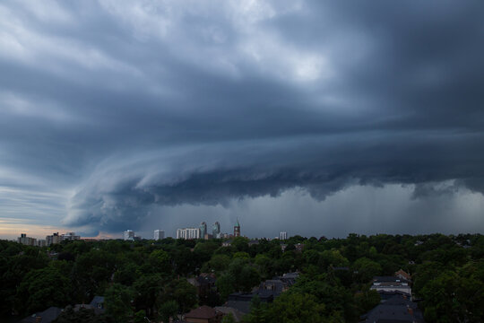 Aerial view of a massive shelf cloud and storm front approaching the city skyline and lush green residential neighborhoods Toronto, Ontario, Canada.