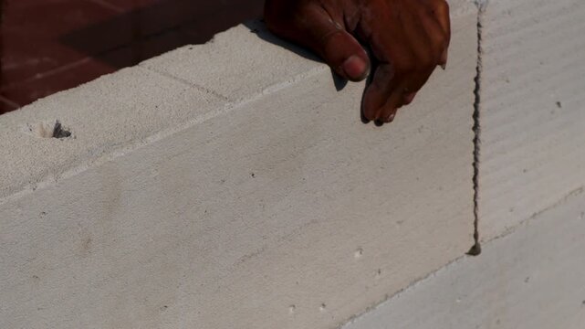 the worker lays white bricks on top of white bricks that have been given mortar
