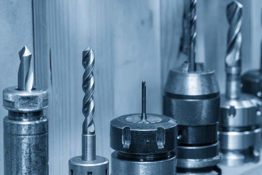 Collection of professional high-speed steel twist drills and countersink bits in an organized tool holder, prepared for a metalworking drilling process in an industrial workshop.