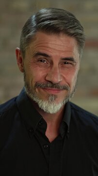 Portrait of happy, confident older man at home looking at camera smiling. Mature age, middle age, mid adult casual guy in 50s, bearded, gray hair.