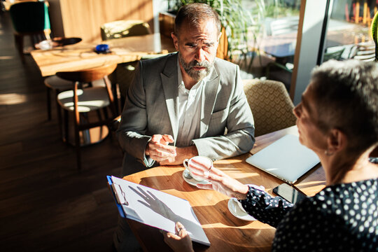 Two business professionals meeting over coffee in a sunlit cafe