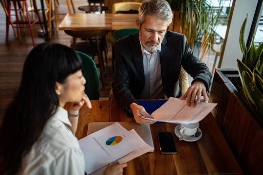 Business colleagues reviewing financial reports at cafe table