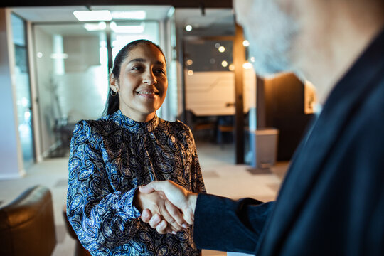 Smiling businesswoman shaking hands with colleague in modern office