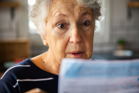 Senior woman reading shocking bill at home