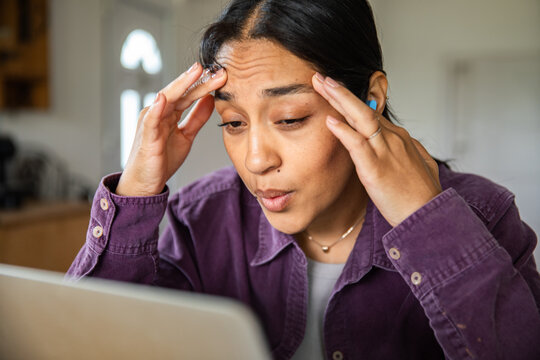 Stressed young woman working on laptop at home
