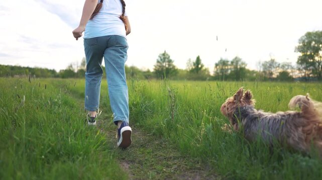 Young girl running with dog. Girl is running outside with a dog. A casual back-view on nature and friendship. A little girl sprinting alongside a lifestyle dog.