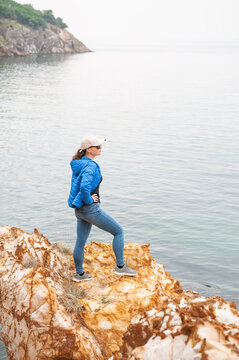 Adventure woman traveler on rocky coastline beside sea