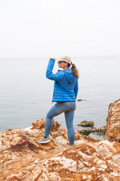 Adventure woman traveler on rocky coastline beside sea