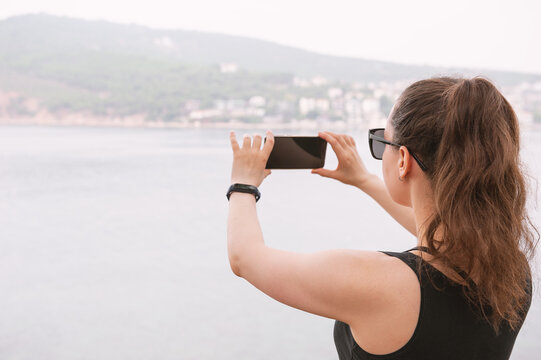 Tourist woman capturing coastal scenery