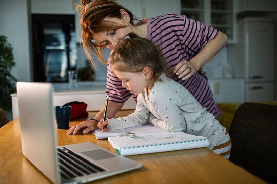 Mother helping daughter with homework at kitchen table