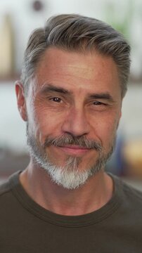 Portrait of happy, confident older man at home looking at camera smiling. Mature age, middle age, mid adult casual guy in 50s, bearded, gray hair.