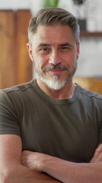 Portrait of happy, confident older man at home looking at camera smiling. Mature age, middle age, mid adult casual guy in 50s, bearded, gray hair.