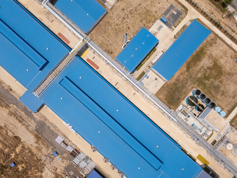 Top-down aerial view of blue cargo barges moored along the riverbank.