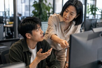 Fototapeta premium Senior Businesswoman Reviewing Junior Colleague Monitor