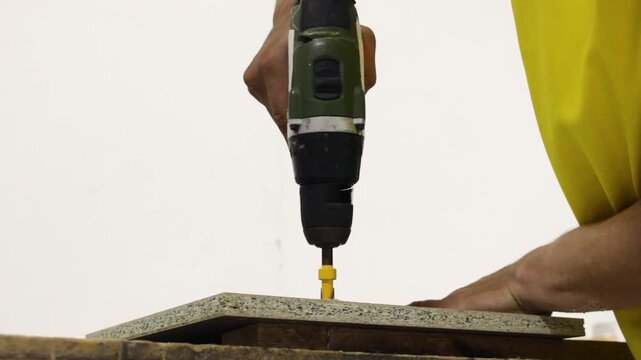A carpenter is working with an electric drill inside an upholstery shop in Neiva, Huila, Colombia. Concept of handmade and work tools