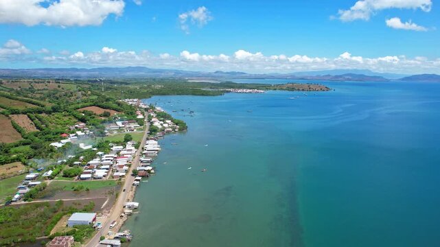 Aerial drone footage of Labuan Jambu village south coastline, with fishermen houses and fishing wooden boats, blue waters, a place to watch whale sharks, in Sumbawa regency, Sumbawa island, Indonesia 