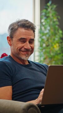 Casual mid adult man with laptop computer in home office, banking online, remote working. Portrait of happy older bearded guy smiling. Businessman, entrepreneur managing business on internet.