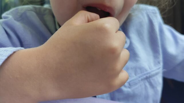 A young boy is shown in a close-up shot as he uses his finger to gently wiggle a loose front tooth, anticipating the natural process of losing baby teeth.