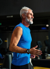 Fototapeta premium Portrait of a senior man exercising in a gym, mature couple running using threadmill machine equipment, healthy lifestyle and cardio exercise at fitness club concepts, vitality and active senior, coac