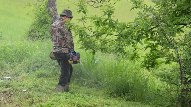 Uomo tagli erba con decespugliatore a filo in montagna