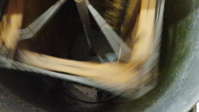 Cinematic close-up of honey flowing inside a rotating extractor machine during traditional beekeeping and honey production process.