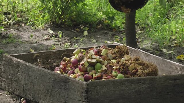 Bio-waste recycling. Compost bin with organic waste. Bio food waste composting bin. Biodegradable material, organic recycling. Waste falling into the compost bin in back yard to create organic compost