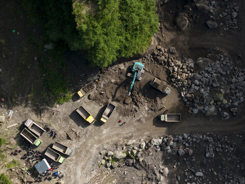 Aerial view of Tambang Pasir Merapi Kali Gendol Sand Mine with excavators loading sand into trucks near large rocks Kecamatan Cangkringan, Daerah Istimewa Yogyakarta, Indonesia.