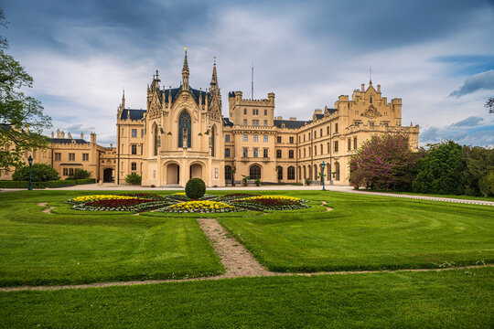 Beautiful Lednice castle chateau with neo gothic architecture and scenic green formal garden parterre lawn under dramatic cloudy sky wide view