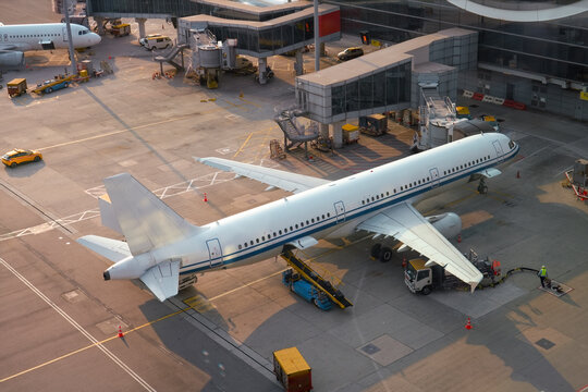 Commercial airplane is connected via a hose for boarding passengers, and ready for tow push back truck preparing for the flight, aerial view
