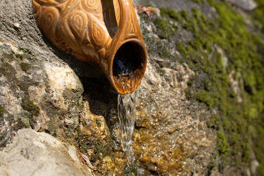 A waterfall in the forest flows from a jug.