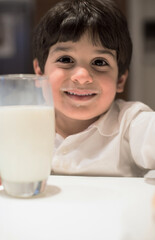 Obraz premium Smiling child with milk moustache holding a glass at modern home iftar during Ramadan Eid dinner