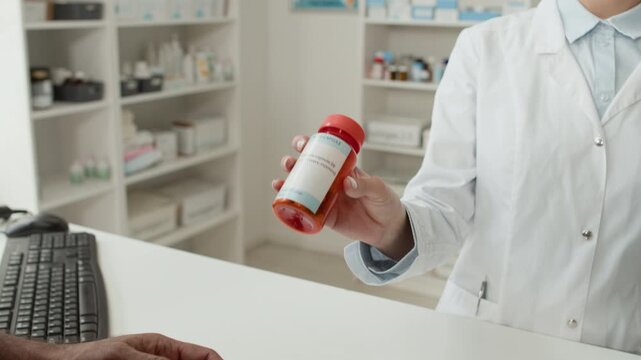 Close up shot of unrecognizable young woman as pharmacist handing bottle of pills to customer while selling medication over checkout counter at pharmacy, copy space