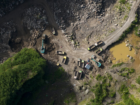 Aerial view of Tambang Pasir Merapi Kali Gendol Sand Mine with excavators, trucks and workers on the rocky terrain Kecamatan Cangkringan, Daerah Istimewa Yogya, Indonesia.