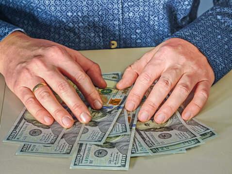 Businessman counting one hundred US dollar banknotes, hands holding stack of USD cash money