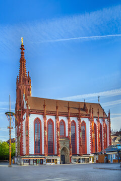 Side view of Marienkapelle church in Wurzburg Germany. Gothic architecture with red and white facade under blue sky