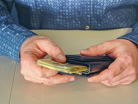 Man putting 200 Polish Zloty PLN banknotes into black leather wallet, financial savings concept