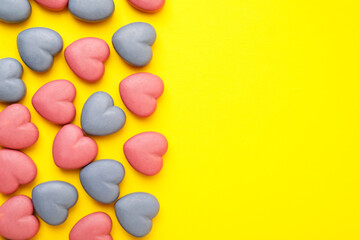 Obraz premium Yummy heart shaped candies on yellow background, flat lay. Space for text