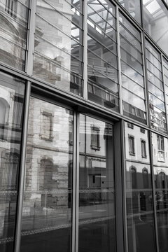 tall windows lead a monochrome composition through glass facade reflection, with urban architecture exterior pattern lines deepening the street view