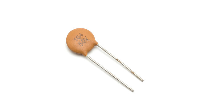 Small ceramic disc capacitor electronic component isolated on a white background, passive electrical circuit part