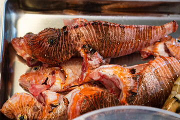Close-up of fresh lionfish (Pterois) prepared for cooking on a metal tray. © Vladyslav