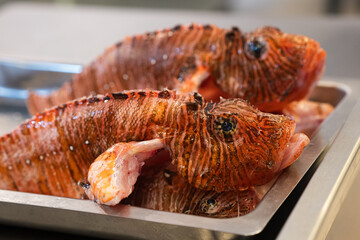 Close-up of fresh lionfish (Pterois) prepared for cooking on a metal tray.  © Vladyslav