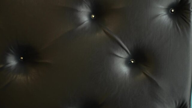 Black button tufted leather upholstery background with metal pins details