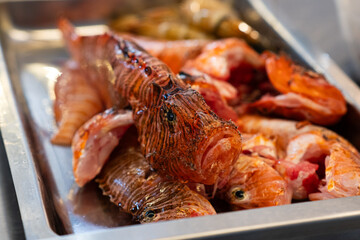 Close-up of fresh lionfish (Pterois) prepared for cooking on a metal tray.  © Vladyslav