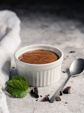 Chocolate mousse dessert in white ramekin with mint and dark chocolate
