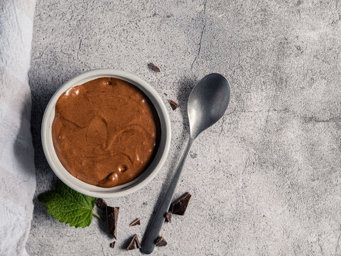 Chocolate mousse dessert in white ramekin with mint and dark chocolate top view and copy space