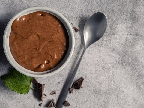 Chocolate mousse dessert in white ramekin with mint and dark chocolate top view and copy space